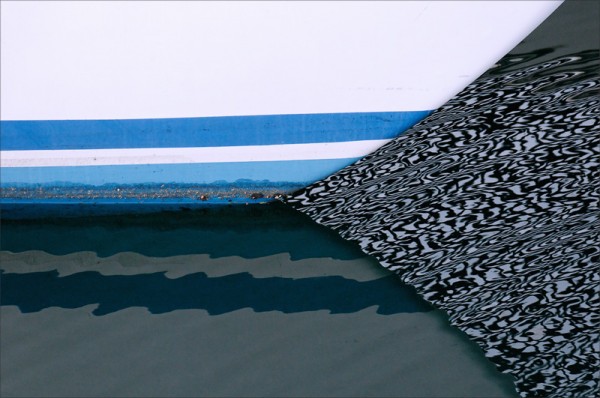 The hull of a boat floating within strongly patterned reflections.