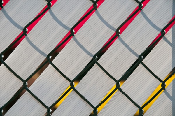 Bright red and yellow showing through gaps in a latticed fence.